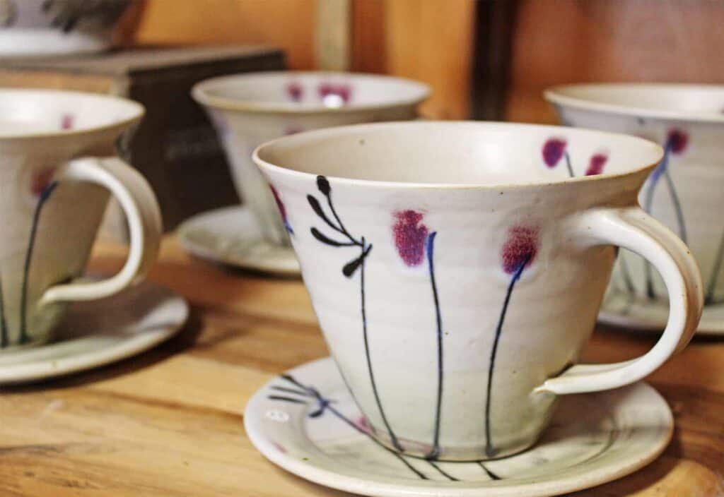 Four ceramic cups and saucers with a floral pattern on a wooden table.