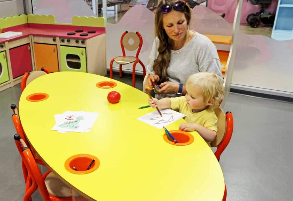 Mère et enfant dessinant dans l'espace enfants, hall des départs, Aéroport de Genève.