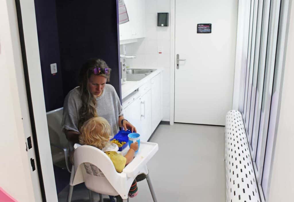 Mère nourrissant son enfant dans la kitchenette dans l'espace enfant de l'aéroport de Genève