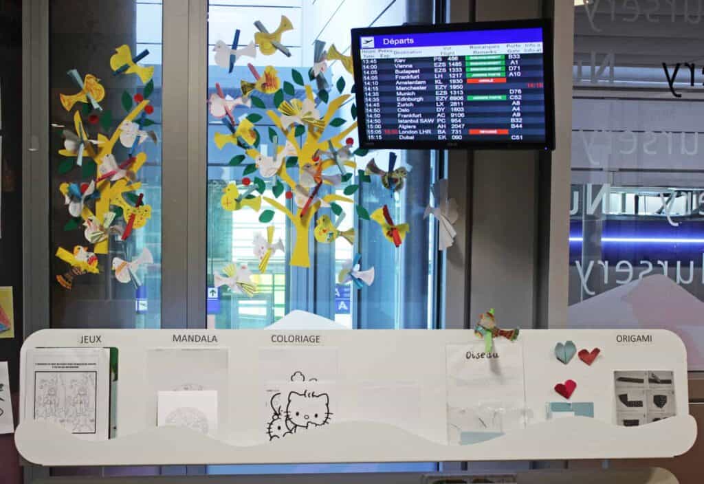 Panneau des départs et feuilles de coloriages dans l'espace enfants de l'aéroport de Genève