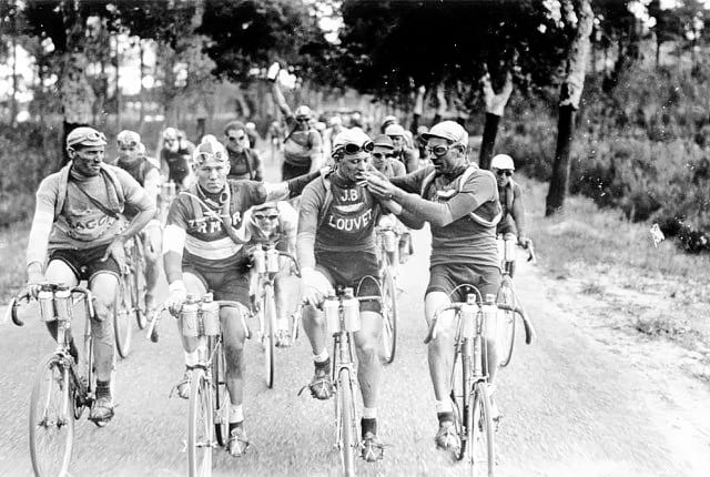 Three cyclists sharing a cigarette whilst riding