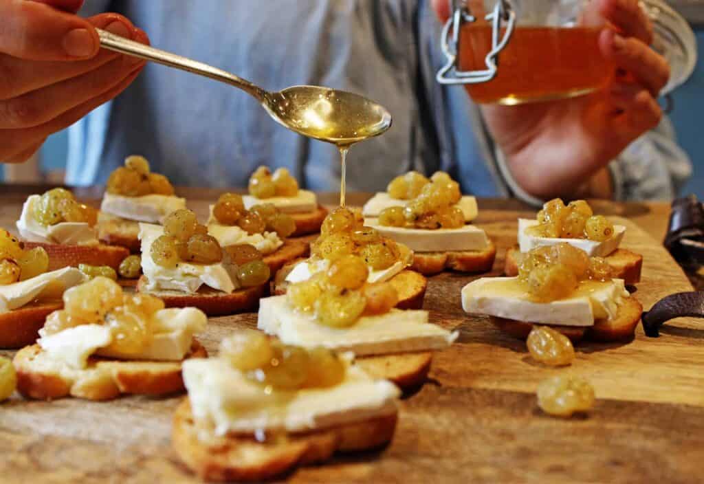 Chef pour a golden yellow sauce over brie and sultana toasts