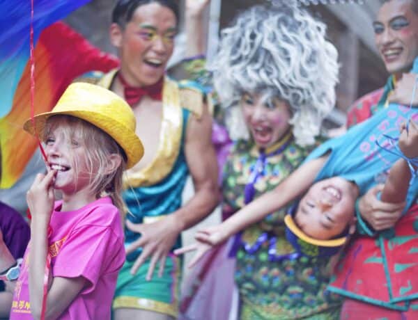 Enfants et animateurs vêtus d’habits colorés riant et jouant au festival d'été Le bonheur des mômes dans les Alpes