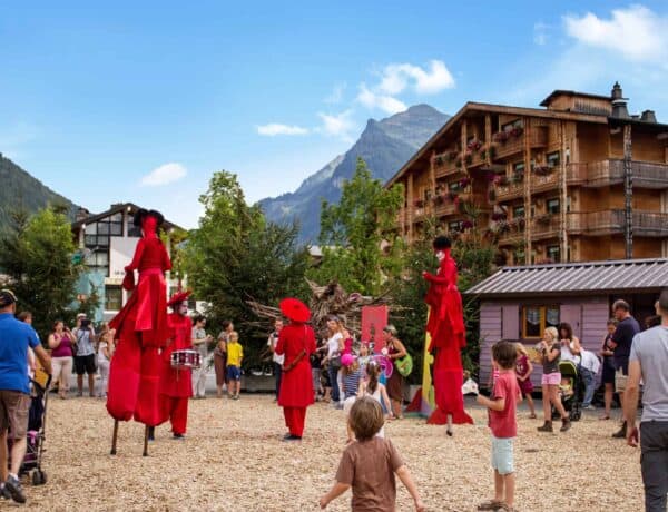 Performers on stilts and red clothing with onlooking children at te Bonheur des mômses festival in Le Grand bornand
