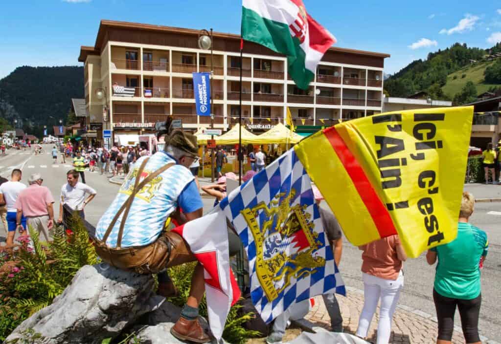 Supporters gear up in all types of clothing to support the riders. This man opted for traditional riding gear and a number of large flags! - Photo credit: James Geen