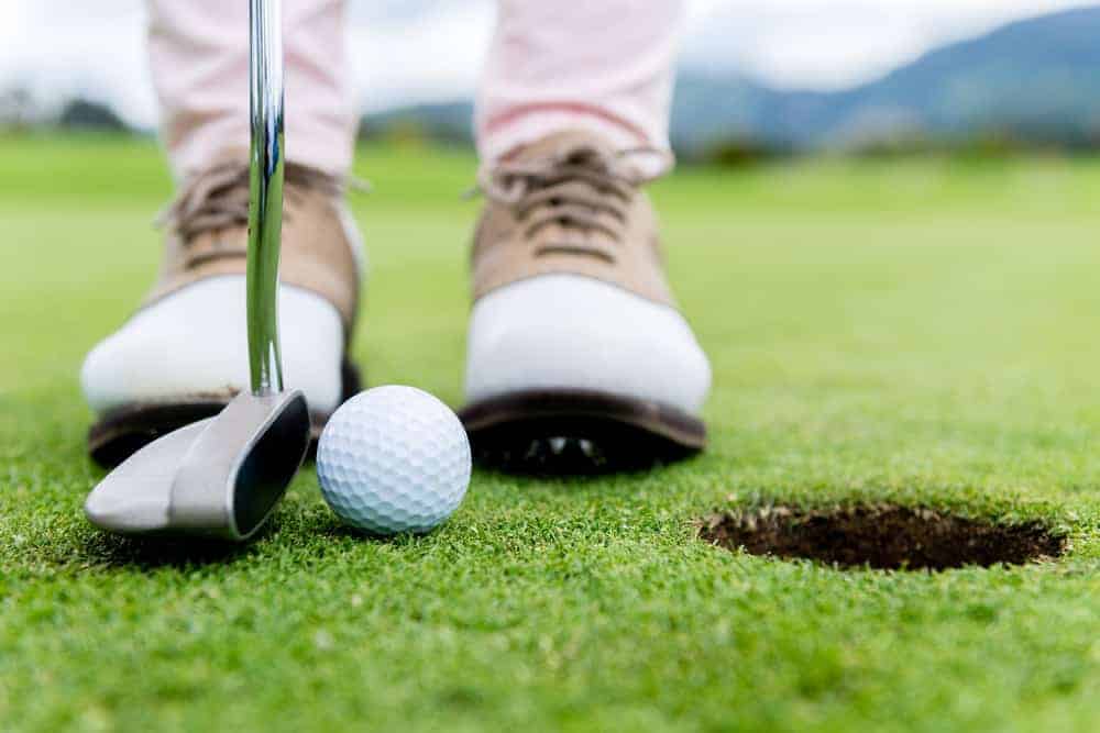 A golfer's feet and putter on Golf de Giez