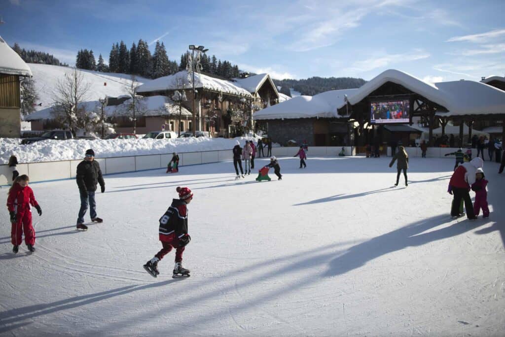 Ice skaters on the open air ice rink in Les Gets on a blue sky day