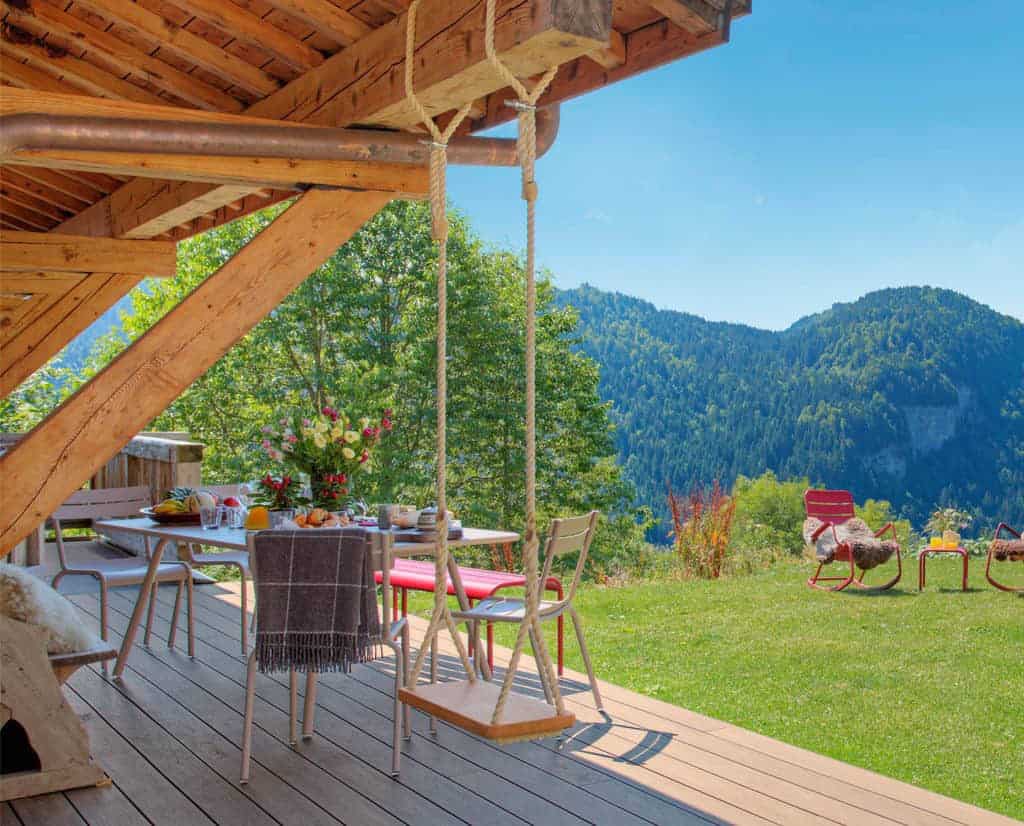 A swing on a sunny chalet terrace with mountain views