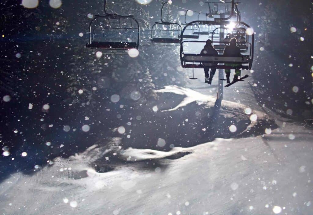 Taking the lift in the snow at the Manigod night skiing