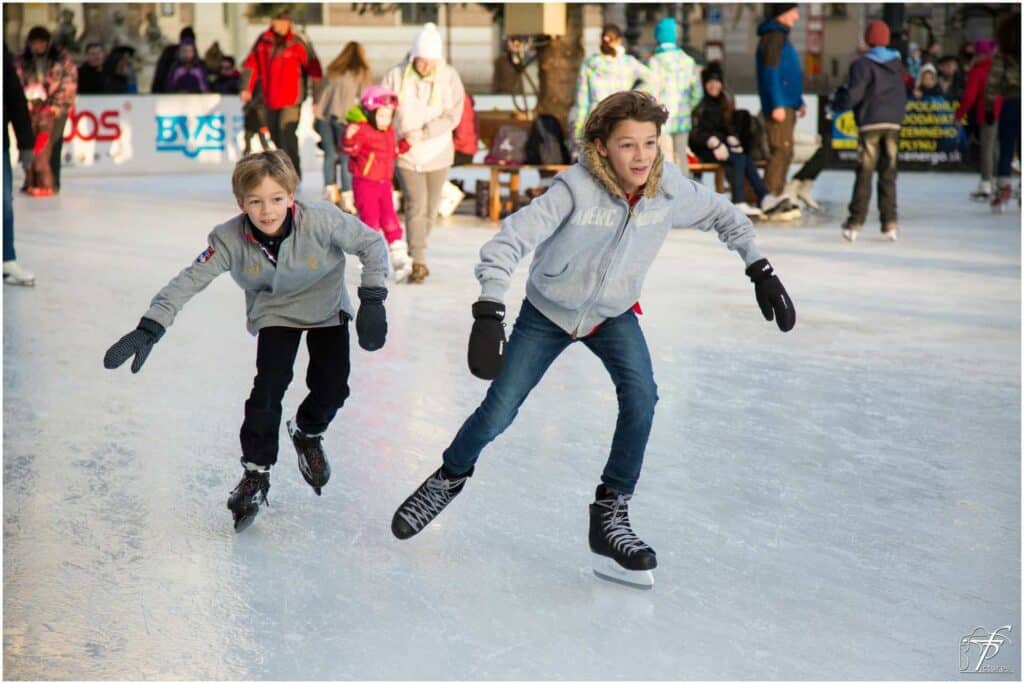 Two boys ice skating on sunny winter's day at the Annecy Christmas market