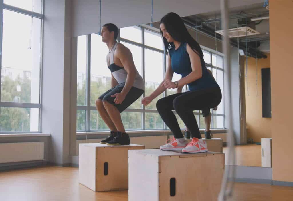 A man and woman doing box jumps as part of their pre ski holiday exercises