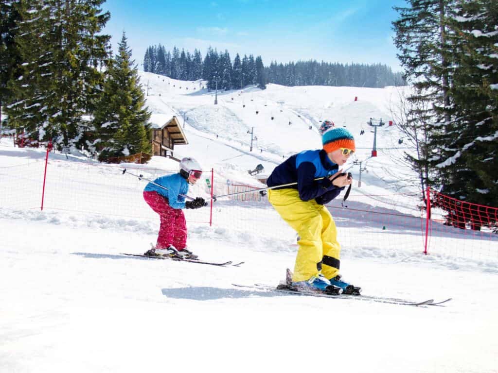 Two children skiing in Manigod dressed in bright ski clothes 