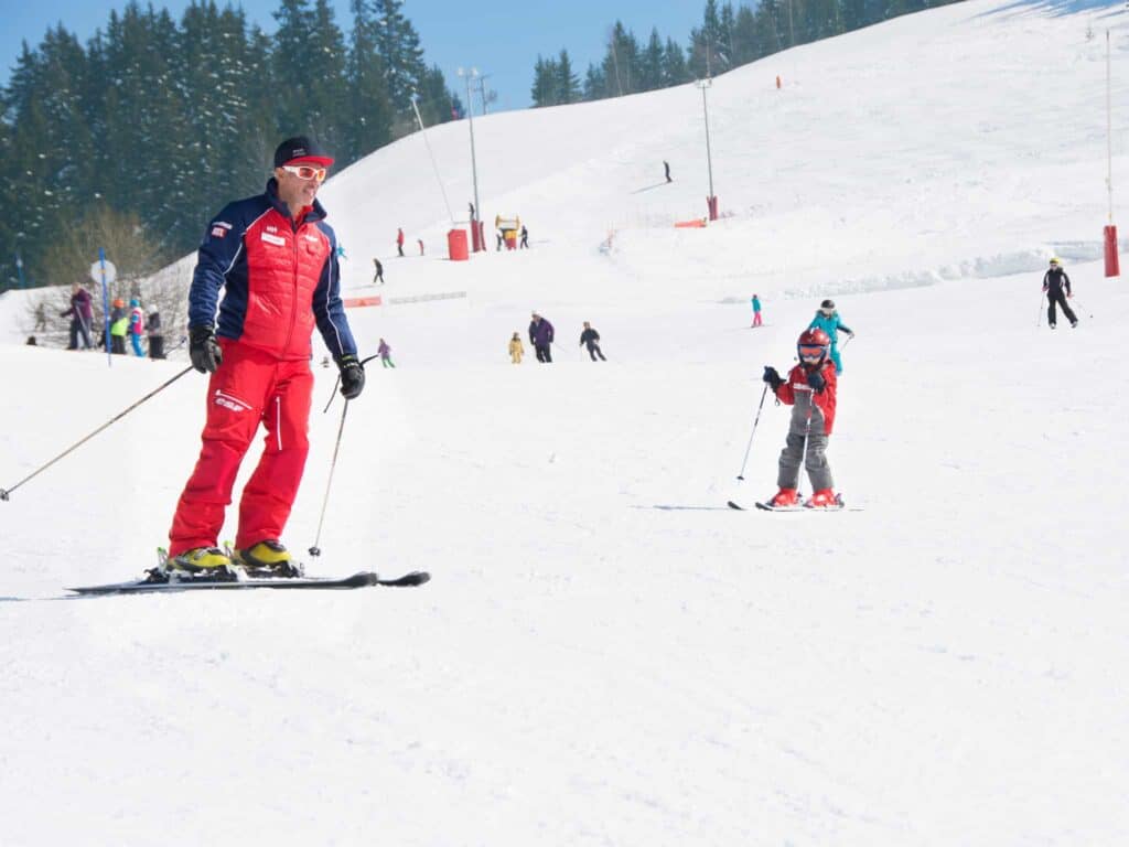 An ESF instructor with a young pupil skiing on a beginner slope in Manigod