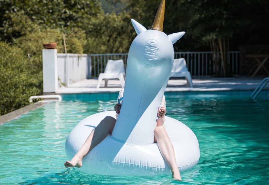 Adolescente assise sur un jeu gonflable dans la piscine extérieure d’une propriété familiale idéale pour des vacances en famille.