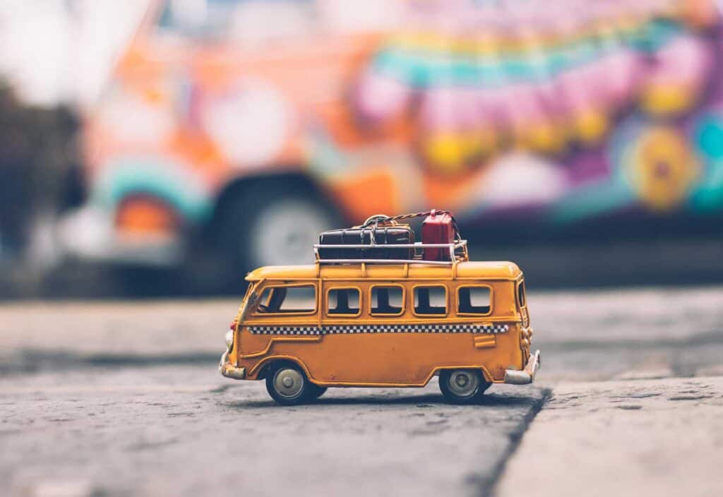 Fourgonnette jaune miniature avec des valises sur le toit