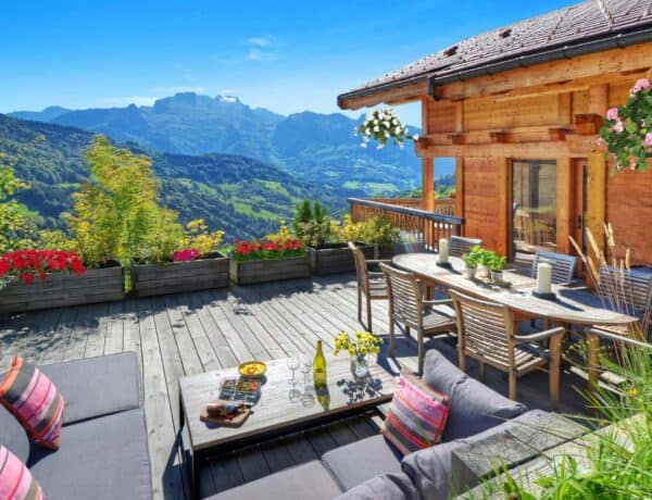 An alpine chalet with spring flowers on the deck and mountains in the background
