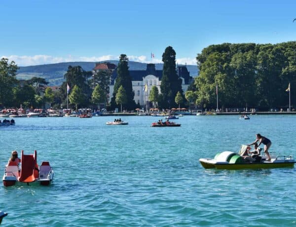Families riding colourful pedaloes on Lake Annecy near the Imperial Palace