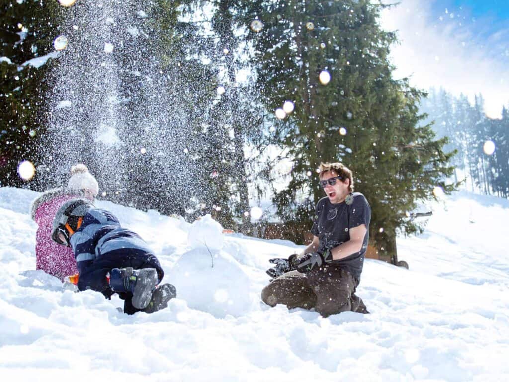 A family having a snowball fight next to a snowman