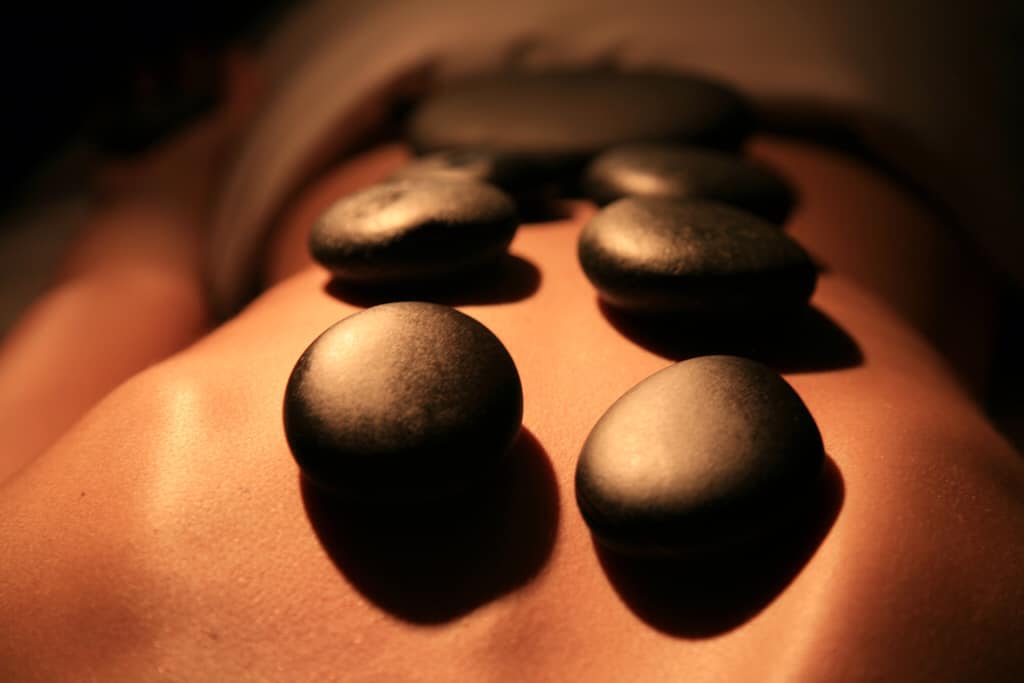 a woman lying on her front with hot stones on her back
