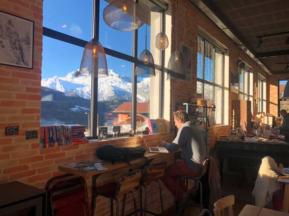 A man works on his laptop with a mountain view