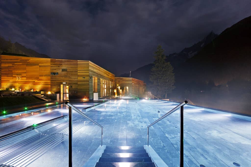 An outdoor swiming pool lit up at night.