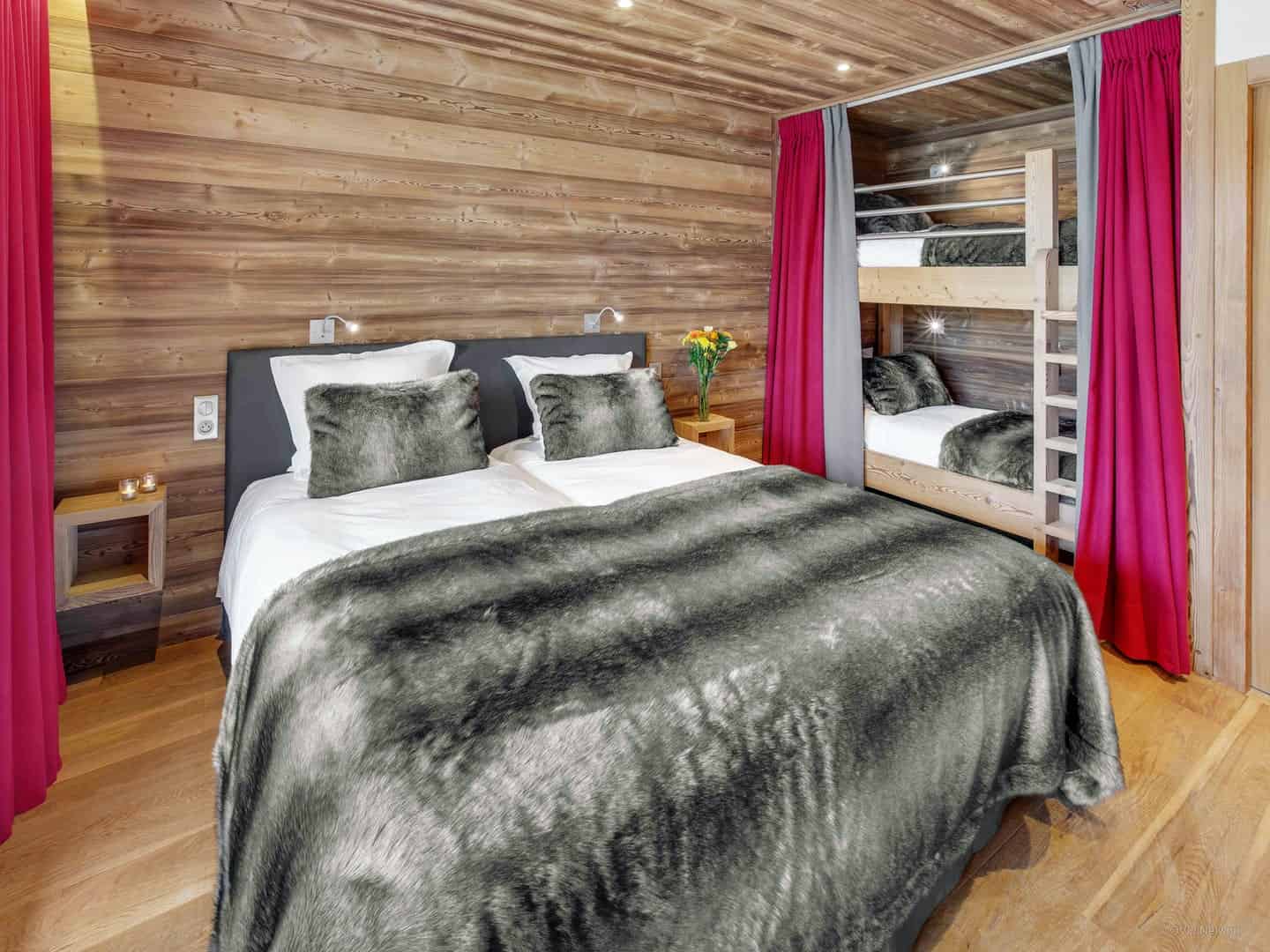 Cool kids' bedrooms: A double bed and two bunks behind a curtain, with an ensuite with two showers and two hand basins at Chalet Meringue.