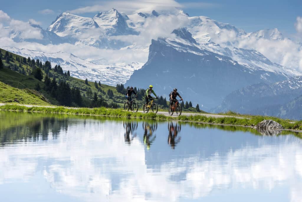 Three cyclists on a path along a mountain lake.