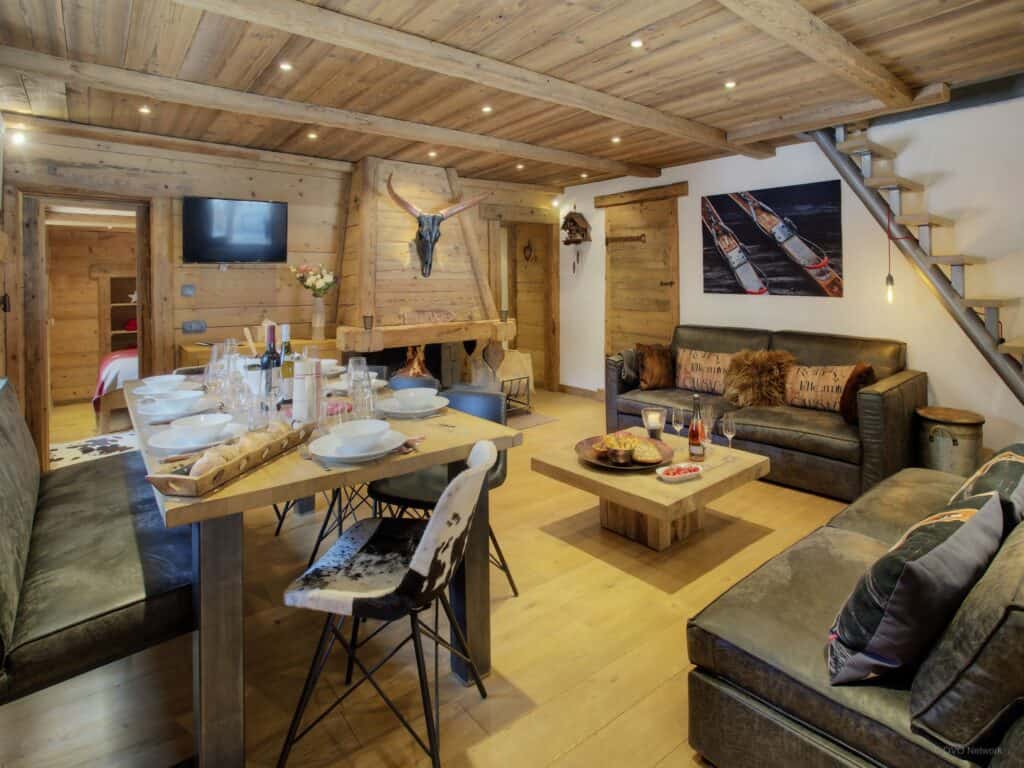 A traditional Alpine living room with an open fireplace, leather sofas and spacious dining table.