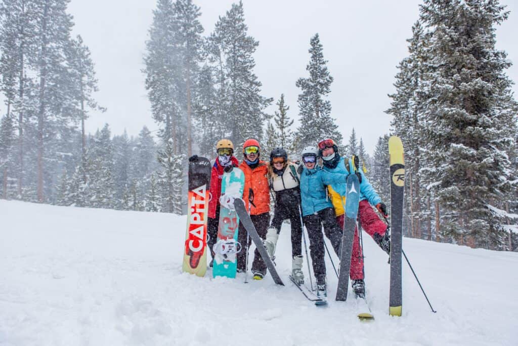 A group of young adults pose on the ski slopes in snow