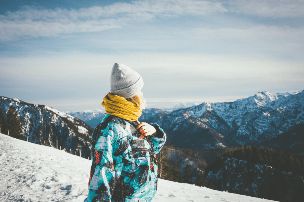 Comment prendre soin de sa peau en hiver ? Une femme en montagne portant plusieurs couches pour protéger sa peau contre le froid.