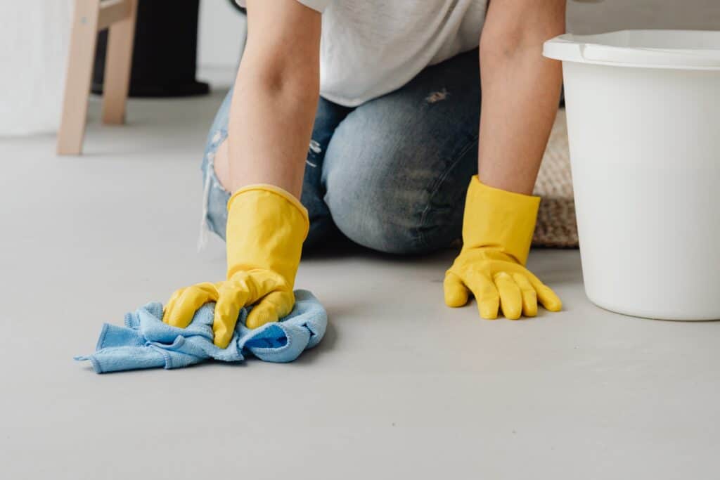 A person kneels down cleaning a floor