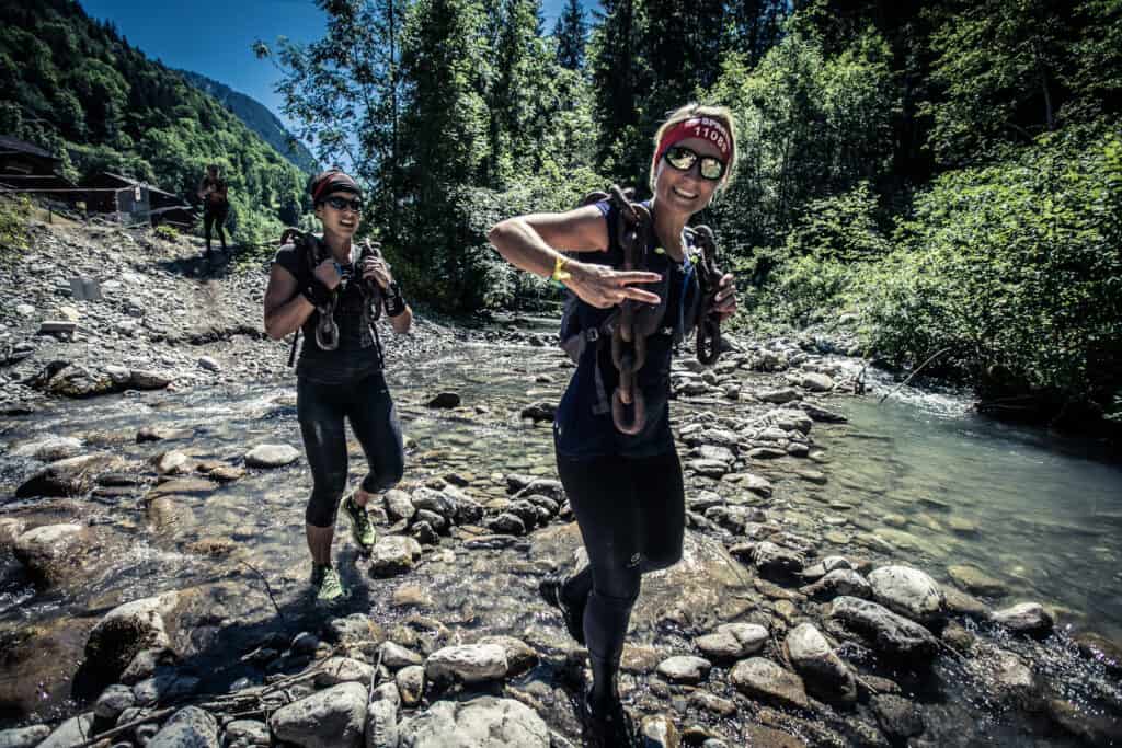 Deux femmes courrent près d'une rivière en montagne. 