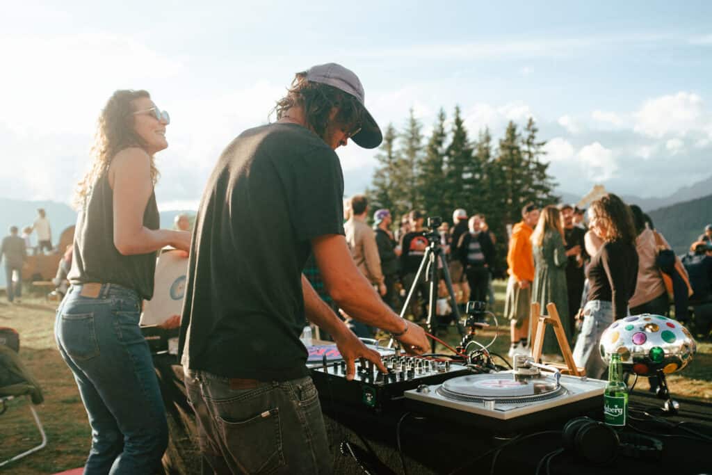 Un homme et une femme font un DJ set dans les montagnes.