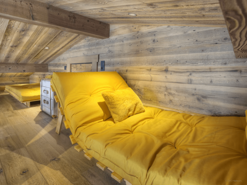 A sloped bedroom with yellow beds.