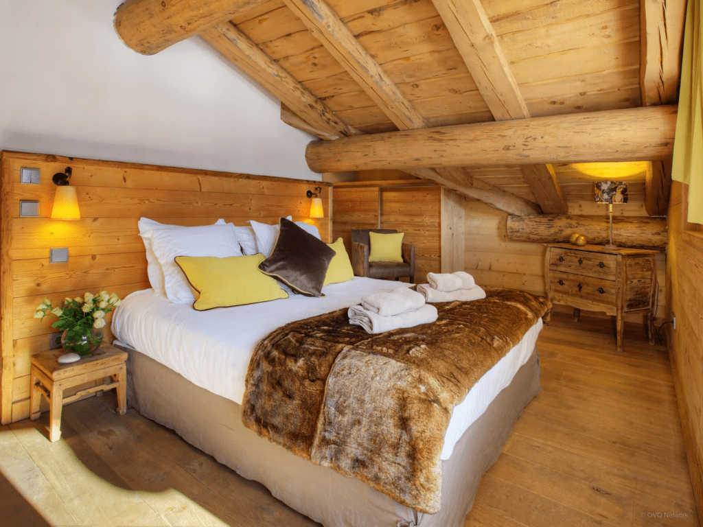 A sloped bedroom with double bed and storage under the eaves.
