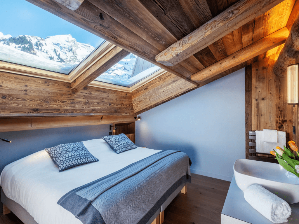 A double bedroom with skylights built into the sloped ceiling providing a mountain view.