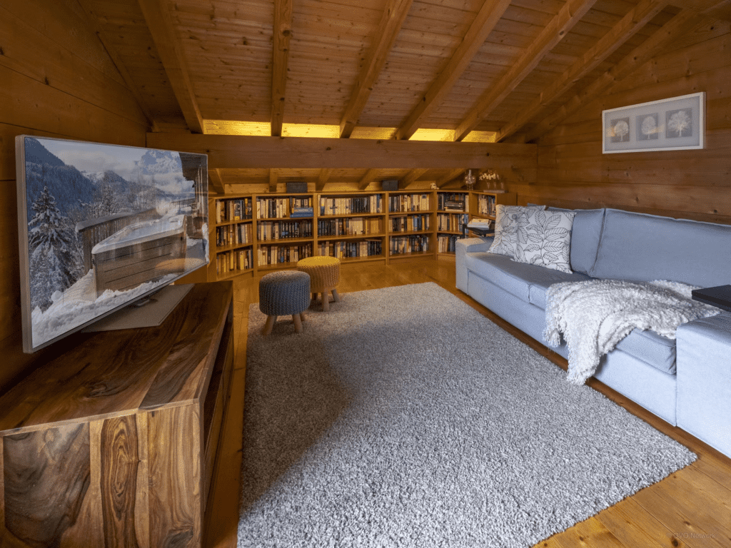 A sloped room with bookshelves and a large sofa and TV.