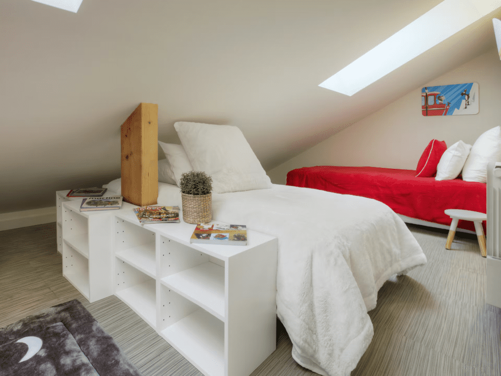 A bright kids room with a low sloped ceiling and storage boxes.