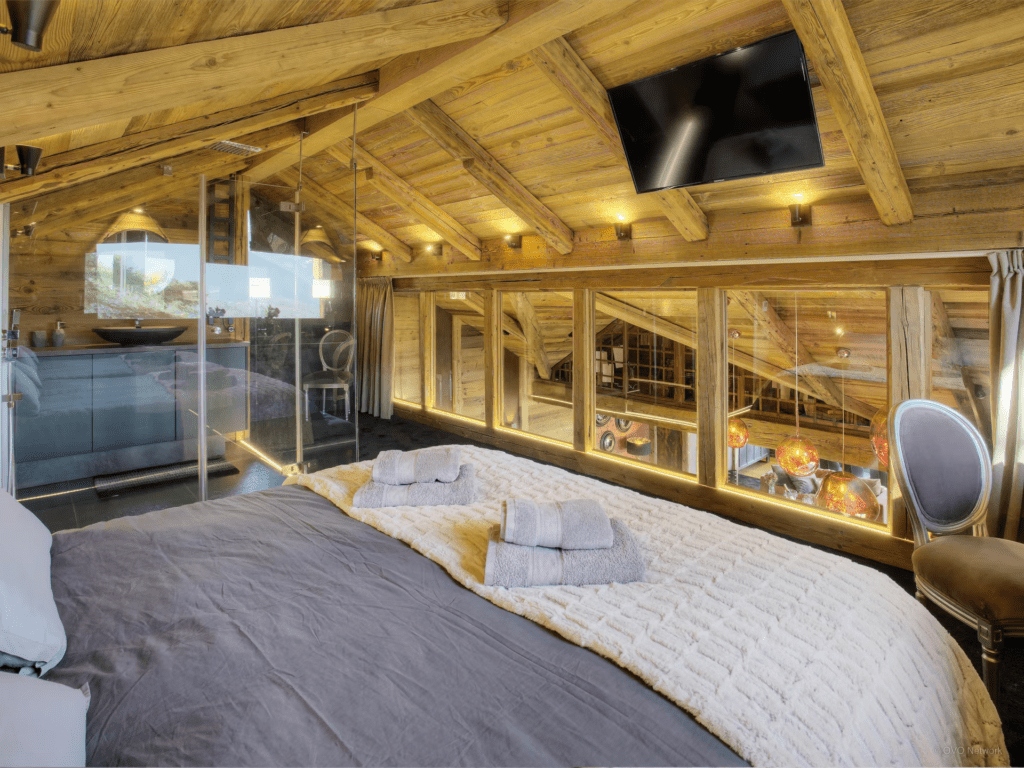 A mezzanine bedroom with a TV built into a sloped ceiling.