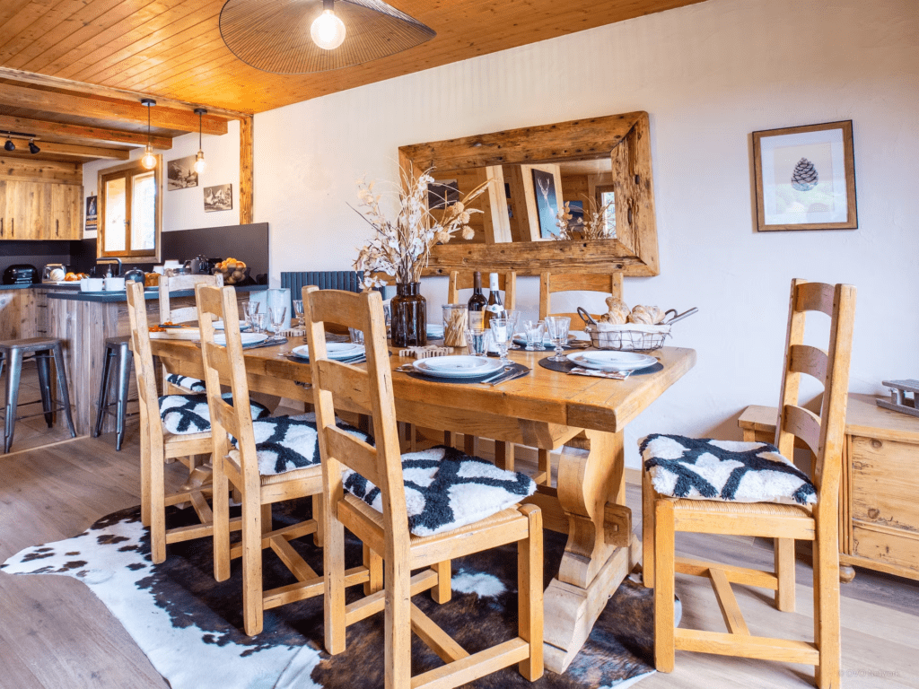 Dining room at Chalet Bonnevie with the table set and a mirror placed above it.