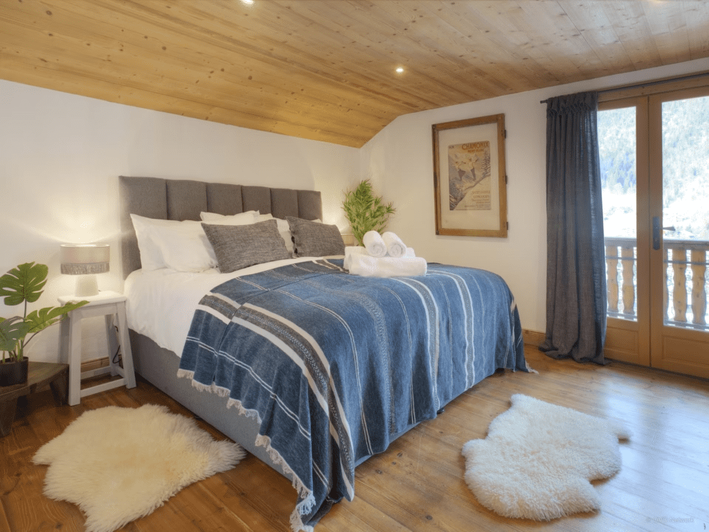 The bedroom at Panormaic Lodge featuring an up-cycled frame with local art, a bed and plants.