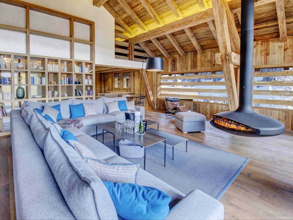 The living room at Chalet Alti which has grey sofas, a suspended fireplace and a bespoke shelving unit.