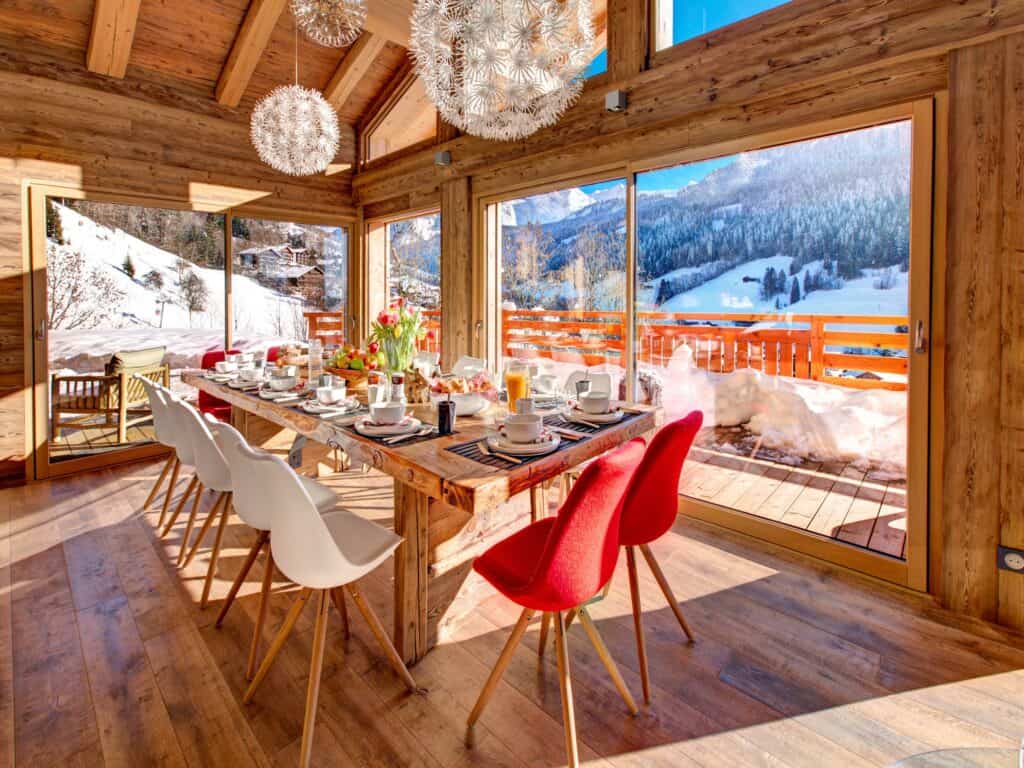 Salle à manger avec vue sur la montagne et chaises rouges au Chalet Alti 