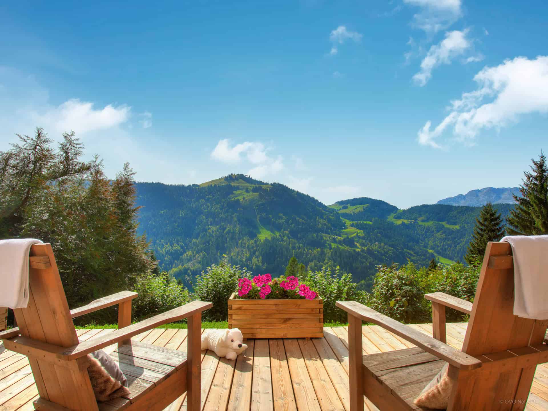 Two wooden chairs with throws and cushions in front of a mountain view at Chalet Charmar