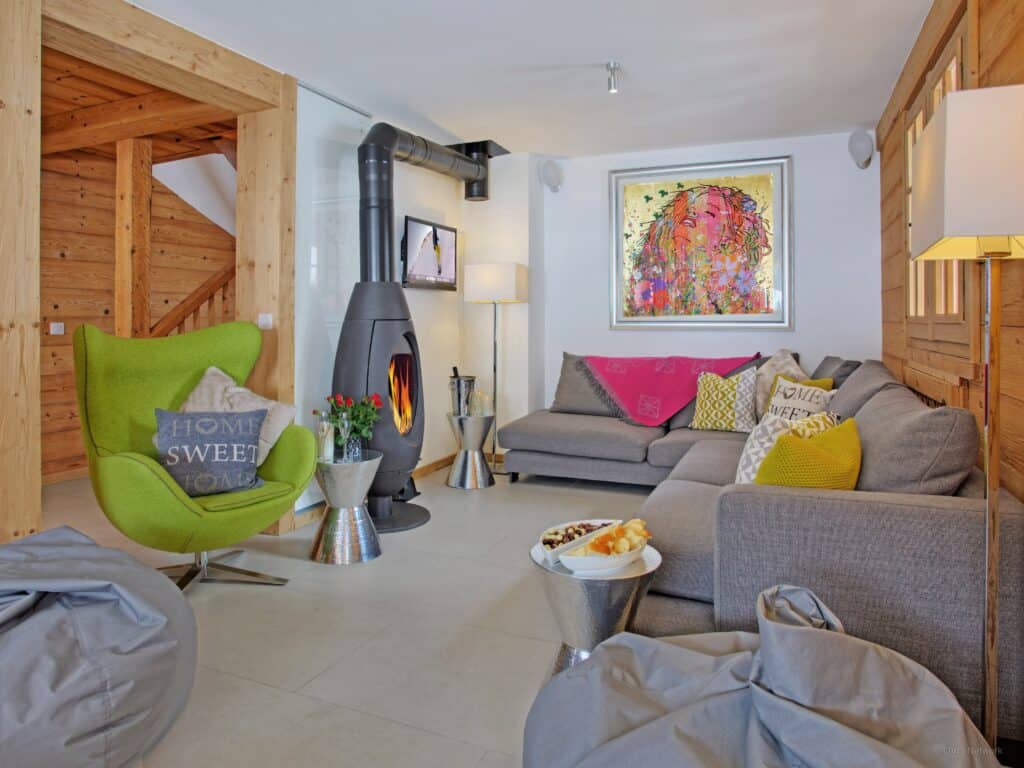 The living room at Chalet Le Mousqueton displaying bold colours and a unique fireplace.