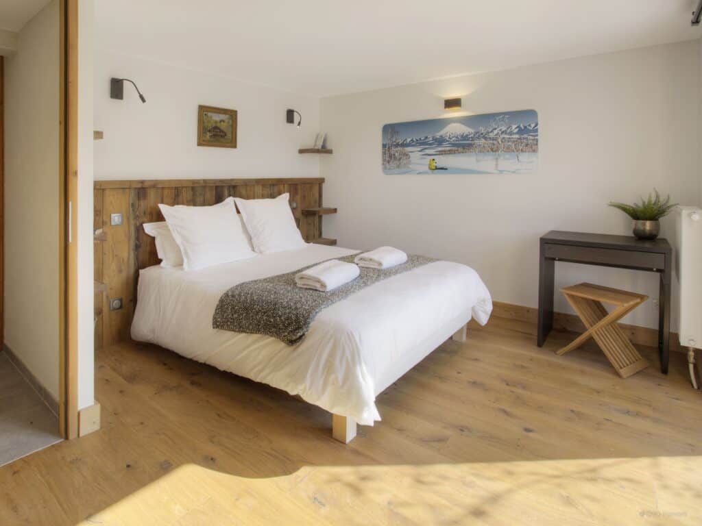 A subtle bedroom at Chalet Zamaro featuring a corner desk and a graphic print on the wall.