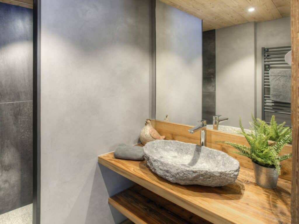 Grey bathroom at Chalet Argali with a plant and stone sink.
