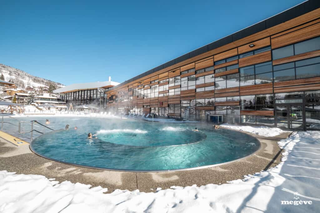 The outside swimming pool of Palais de Megève surrounded by snow.
