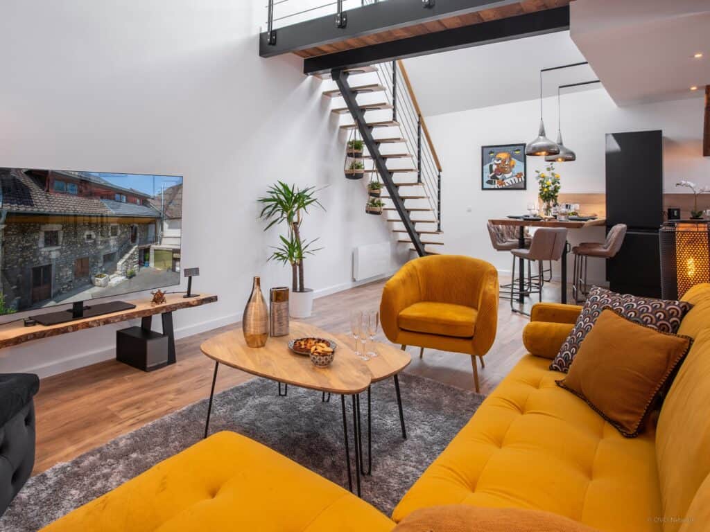 The contemporary living space at Loft Yaute with yellow sofa, armchairs and plants
