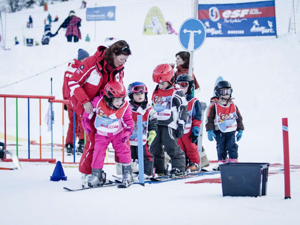 De jeunes enfants apprenant à skier avec une monitrice de l'ESF.